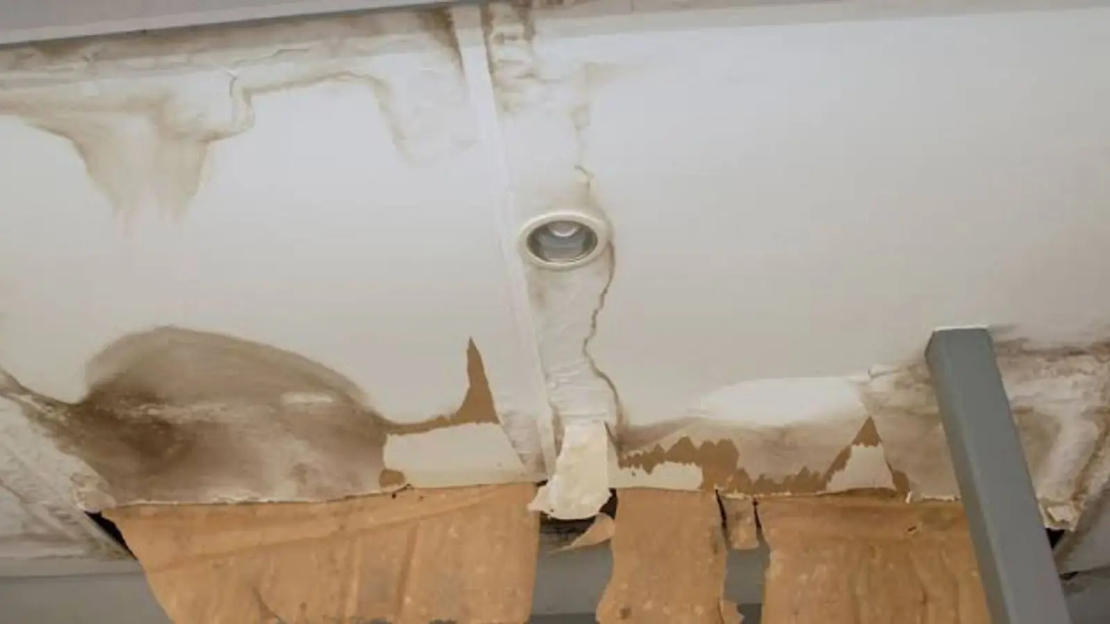 Ceiling around a light fixture stained and sagging from a leak